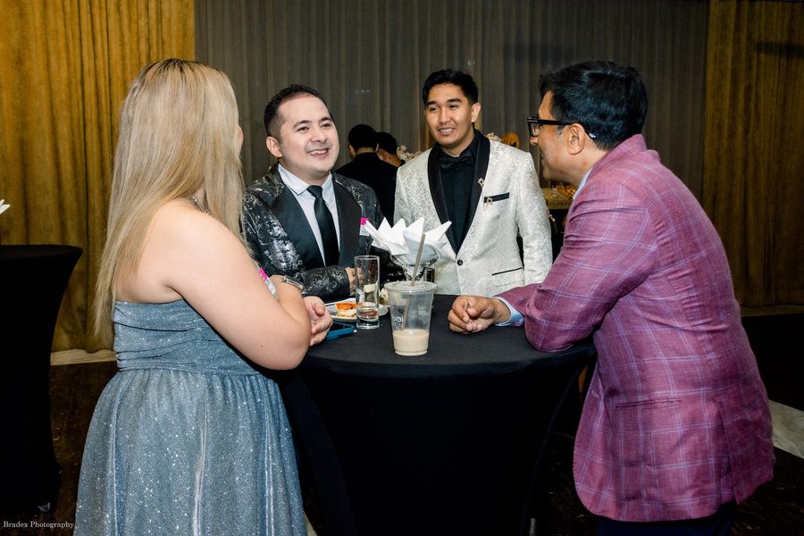 Guests in brocade jackets talking at a cocktail table at the November 2025 gala
